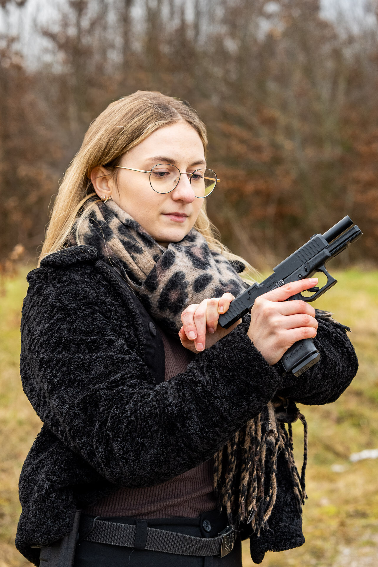 Model zeiht den Schlitten einer Fake Waffe zurück.