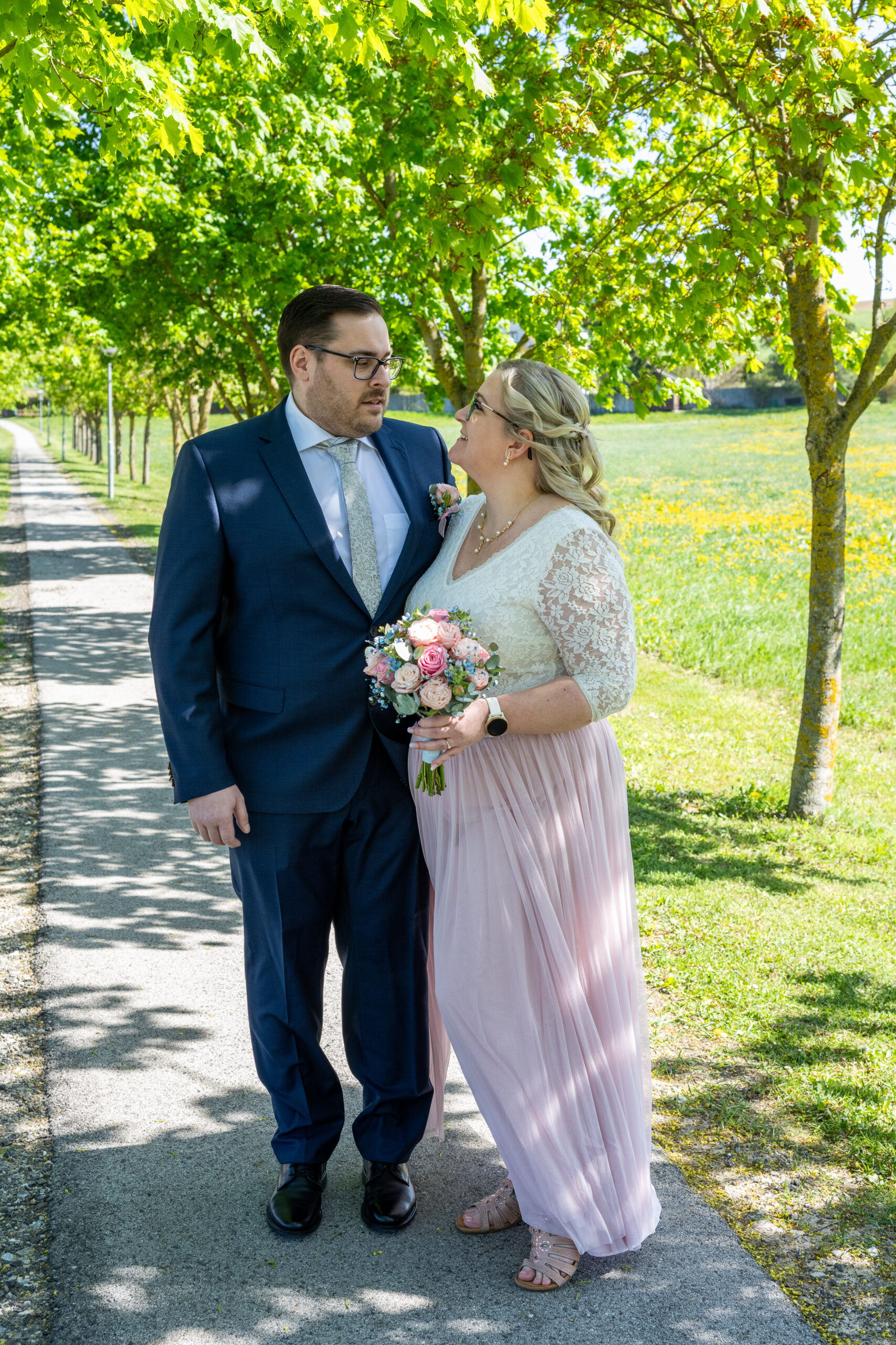 Brautpaarfoto in der Allee. Das Brautpaar sieht sich verträumt und liebend an.
