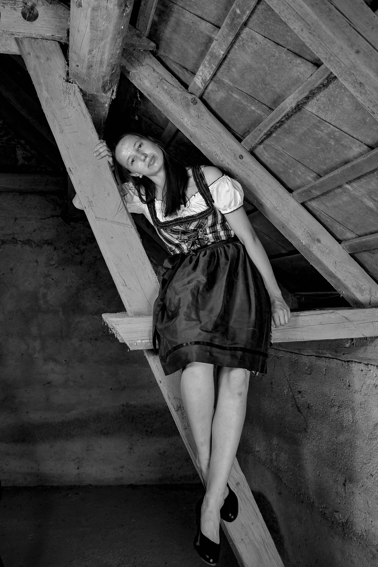 Model sitzt auf einem Holzbalken am Dachboden
