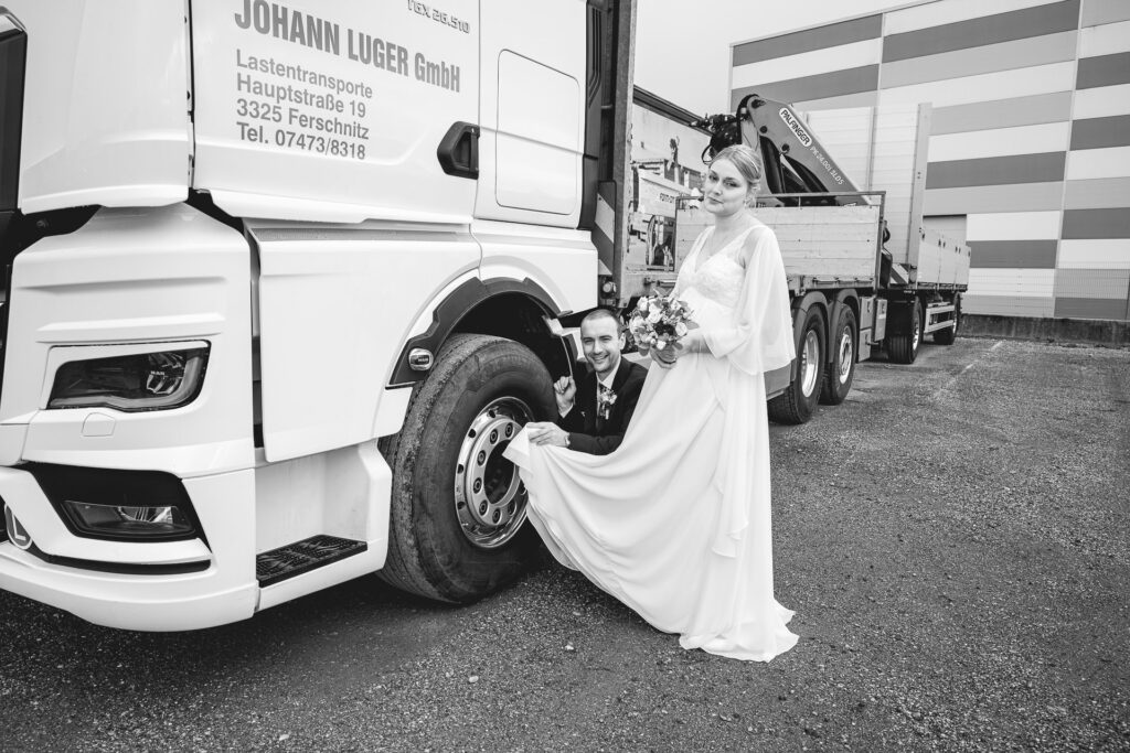 Bräutigam putz mit dem Brautkleid die Felge des LKW